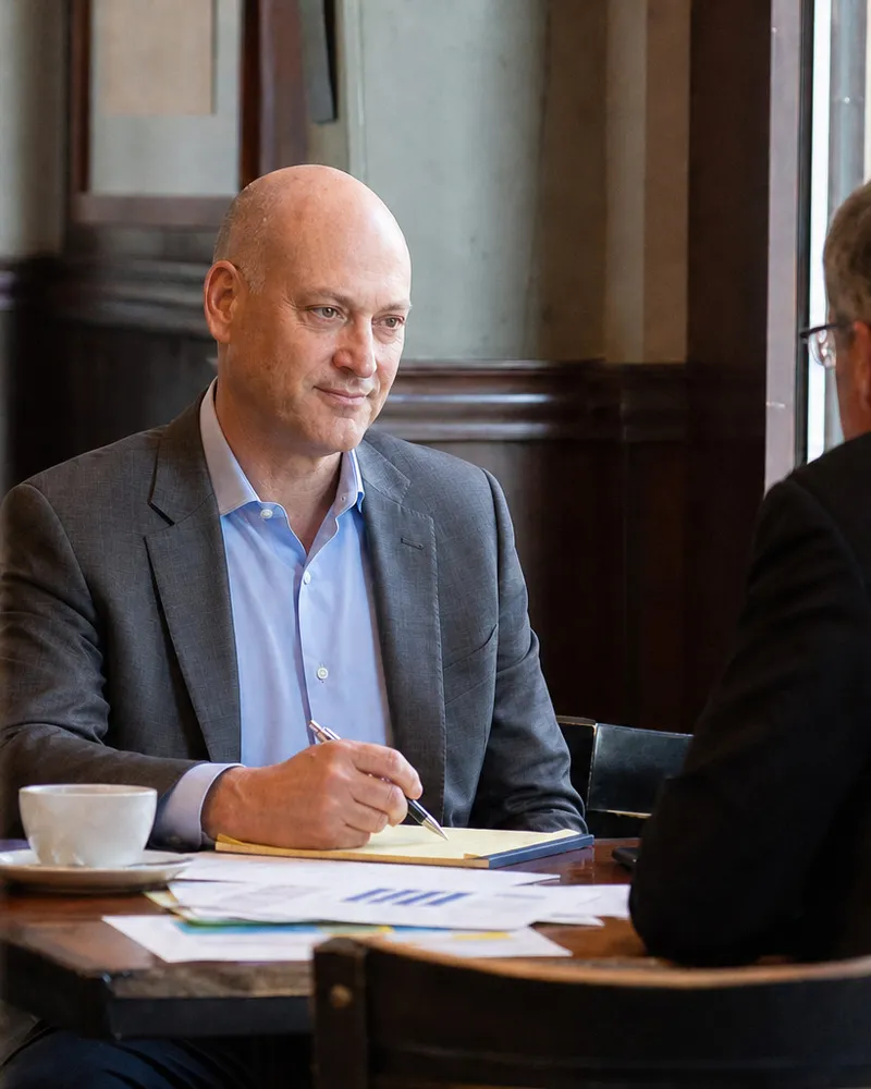Peter DeCaprio taking notes at a café table during a breakfast meeting with an investor